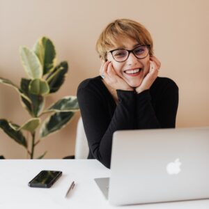 Uśmiechnięta kobieta przy laptopie podczas konsultacji online
