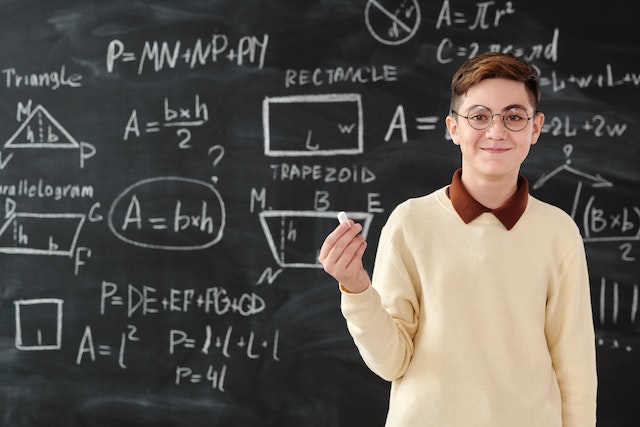 Chłopiec w swetrze rozwiązuje zadanie matematyczne